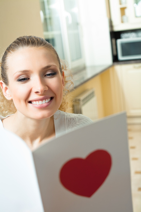 Young happy smiling woman, reading valentine card at home